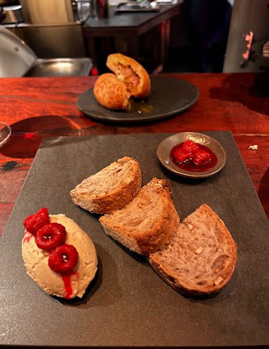 Prato de entrada do restaurante Anchíta, com pedaços de pão cortados e frutas vermelhas.