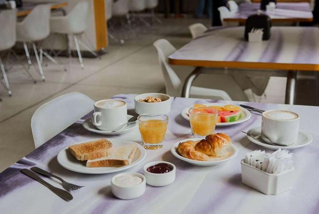 Mesa de café da manhã com pratos de pães, frutas e sucos