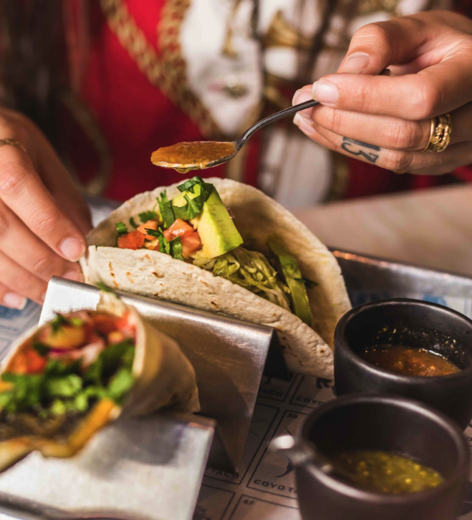 Coyo Taco Restaurante em Lisboa - Mãos segurando tacos comida.