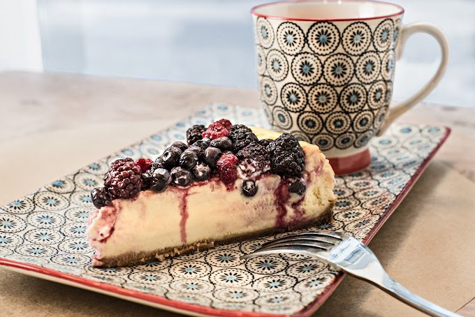 Cheesecake de frutas vermelhas acompanhado de uma xícara