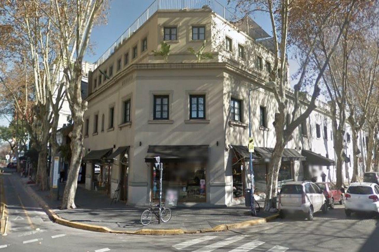 Fachada do hotel de esquina em meio às árvores