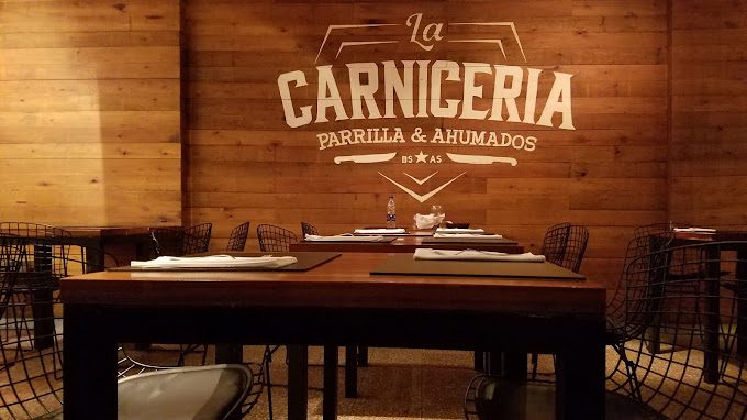 Ambiente interno do restaurante La Carniceria com logo na parede