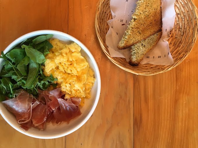 Bowl de ovo mexido com presunto parma, rúcula e acompanhado de pão