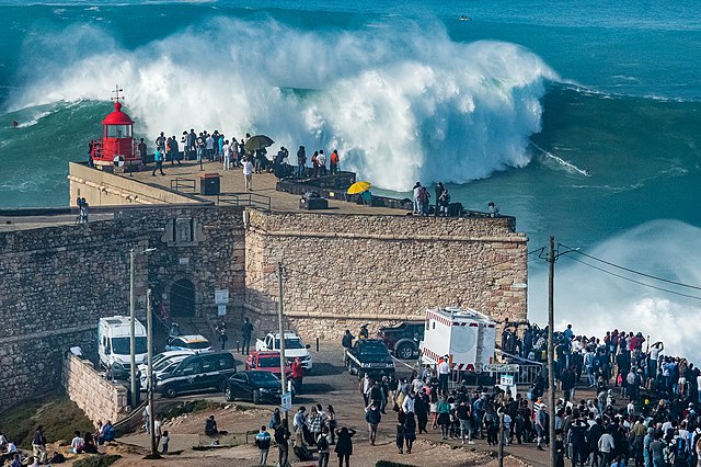 Pessoas vendo as ondas gigantes no Forte São Miguel Arcanjo, em Nazaré, Portugal.