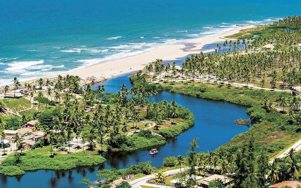 Visão aérea da praia de Imbassaí com o rio e o mar em meio a vegetação