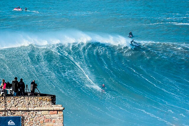 Surfistas pegando uma onda gigante em Nazaré, Portugal