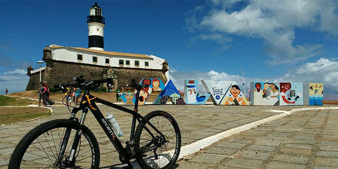 Bicicleta em frente ao letreiro de Salvador na Praia do Farol da Barra