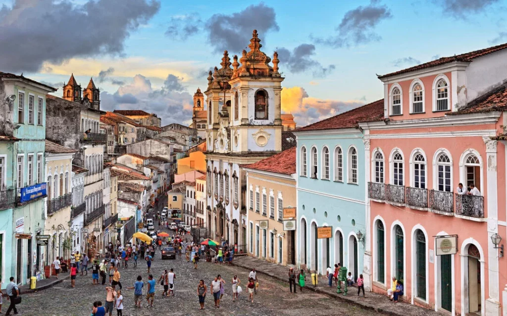 Rua de Salvador na Bahia com pessoas caminhando e prédios antigos ao redor. 