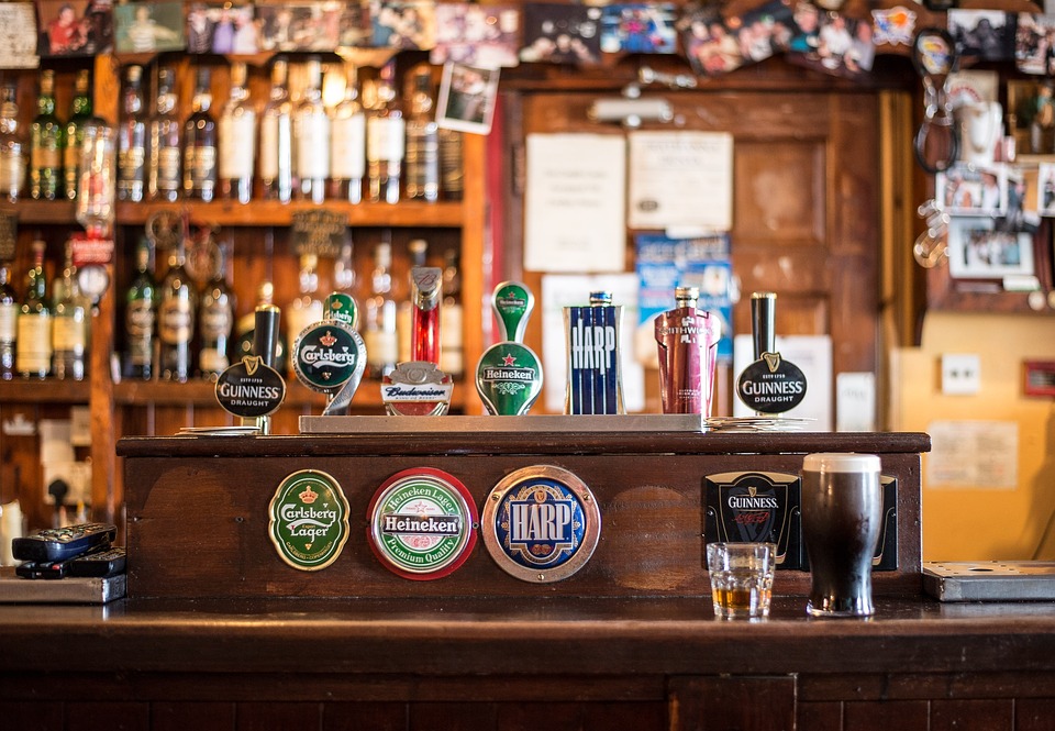 Balcão de um bar com diferentes cervejas e garrafas de bebidas.