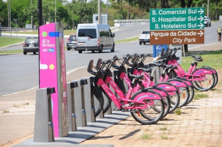 Bicicletas cor de rosa por aplicativo. Estão em Brasília com uma placa de fundo.