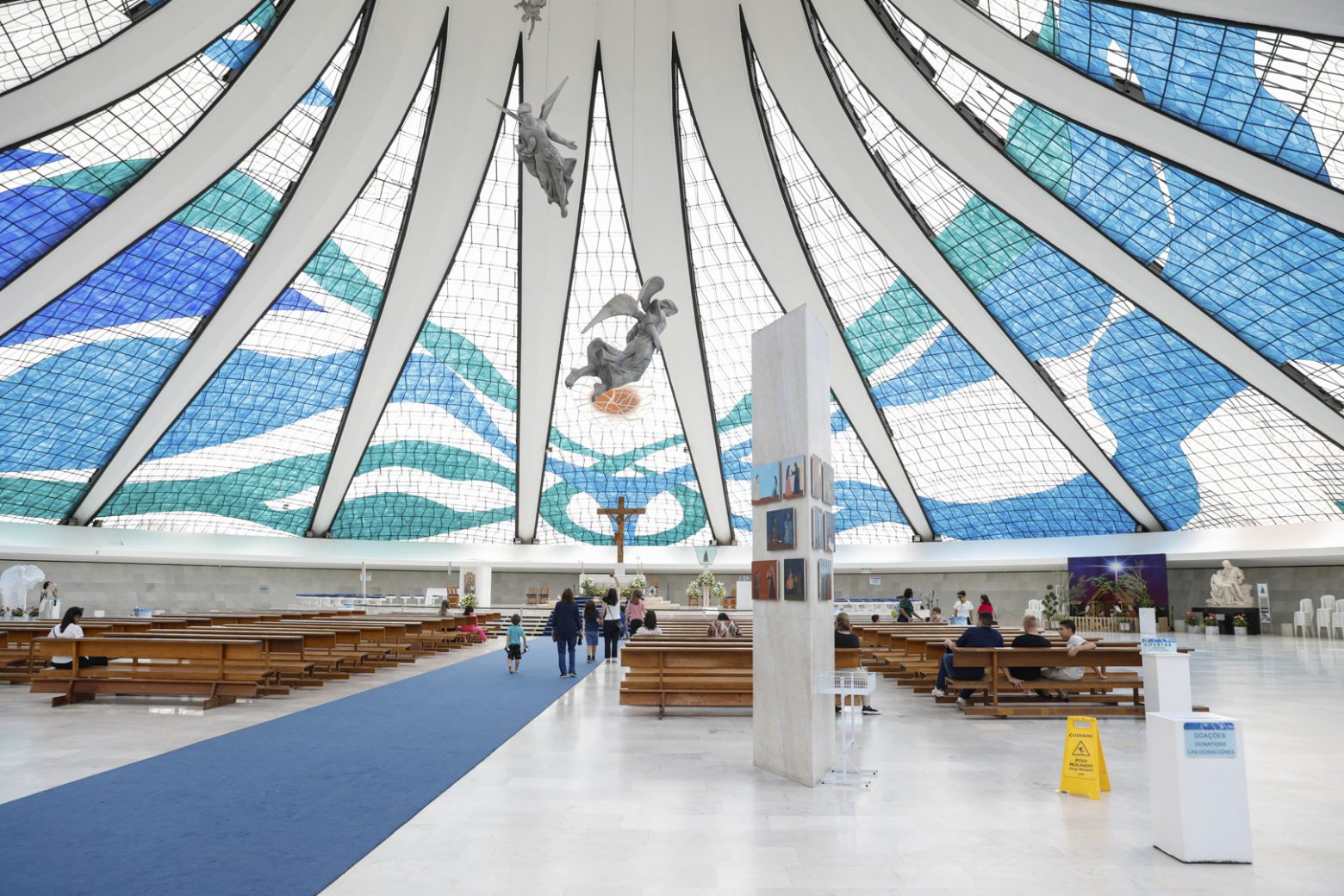 Anjos suspensos no interior da Catedral de Brasília. Vitrais, altar e pilar com Vida de Maria, pinturas de Athos Bulcão.