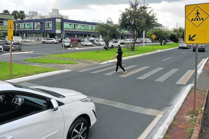 Pessoa atravessando faixa de pedestres, carro parado, Brasília