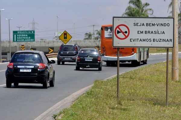 Placa que orienta a evitar buzinar e carros na rua de Brasília, DF