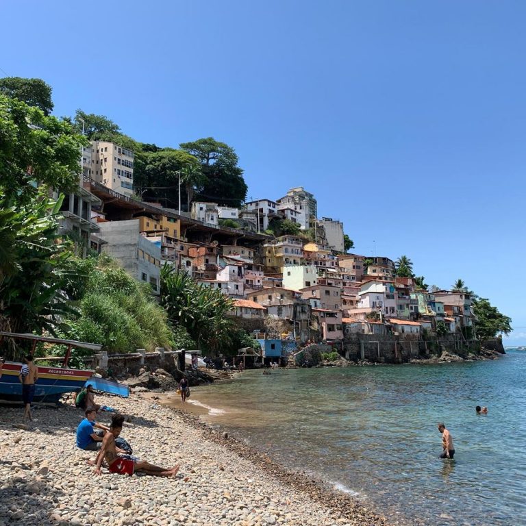 Praia do Solar do Unhão em Salvador Bahia - Na imagem mostra a areia da praia com casas posicionadas sobre um morro.