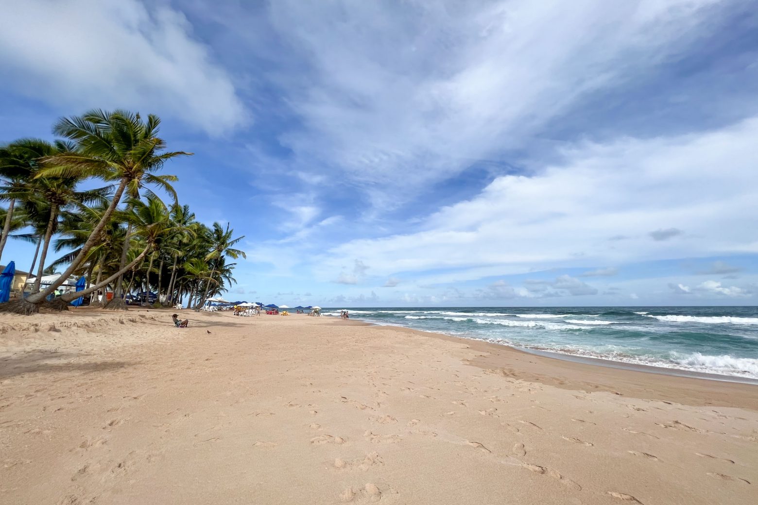 Praia de Stella Maris em Salvador, BA - Na imagem mostra o mar ao fundo e areia a frente com coqueiros a vista.