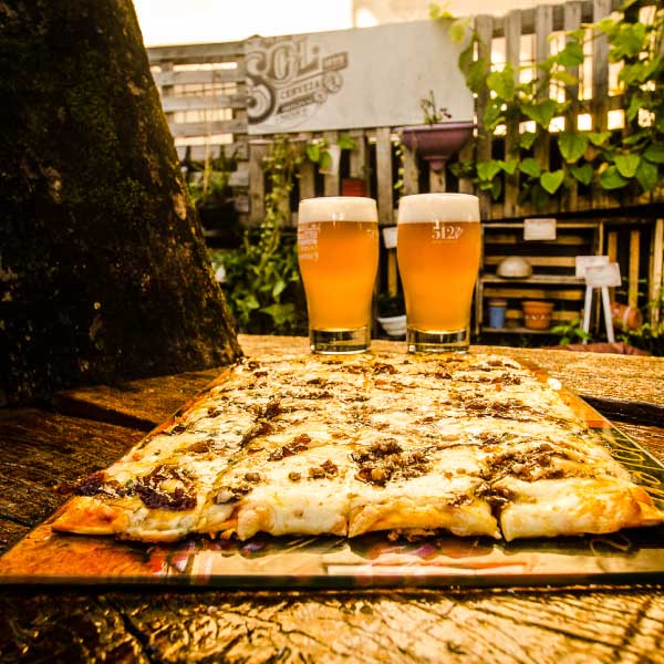 Duas cervejas e pizza na mesa do Espaço Cultural 512, Porto Alegre