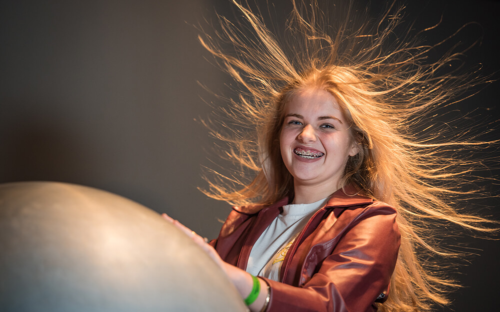 menina fazendo experimento de eletrostática com cabelo em pé. Porto Alegre.