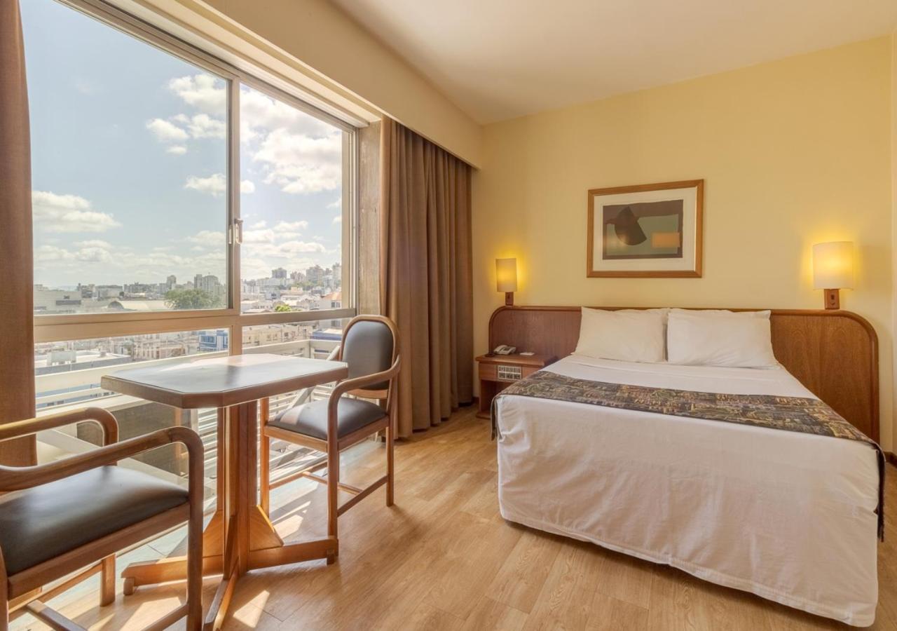 Quarto Ritter Hotel, cama, mesa e duas cadeiras. janela com vista. Porto Alegre