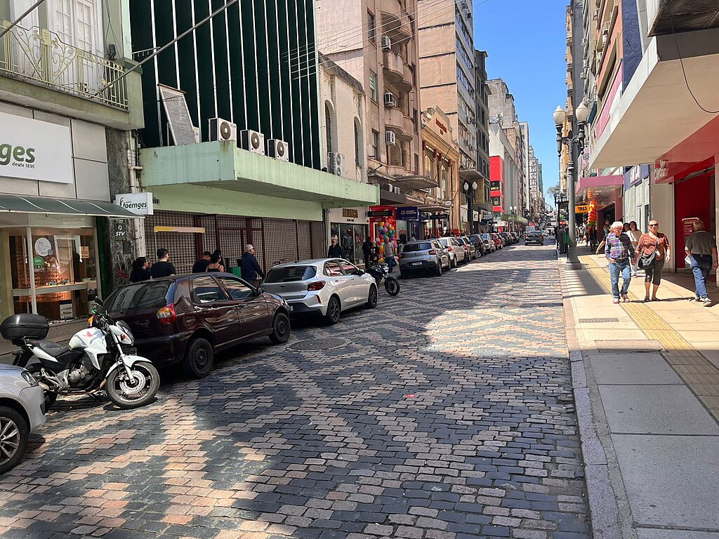 Calçamento tombado da Rua da Praia, Porto Alegre. Lojas e carros. Pedestres.