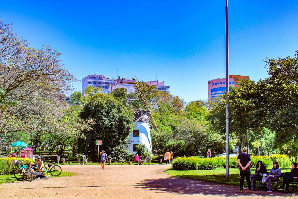 Imagem do Parque de Porto Alegre Parcão, com árvores e pessoas caminhando. 