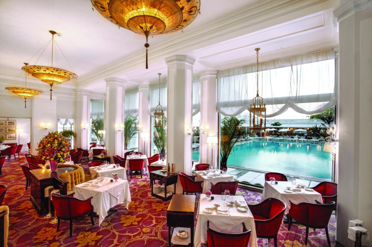 Copacabana Palace - Salão interior com tapete vermelho e lustre dourado. Piscina no fundo. Rio de Janeiro