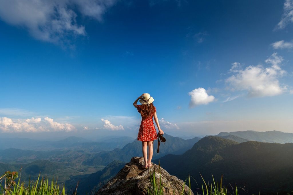 Mulher no topo de uma rocha olhando a paisagem